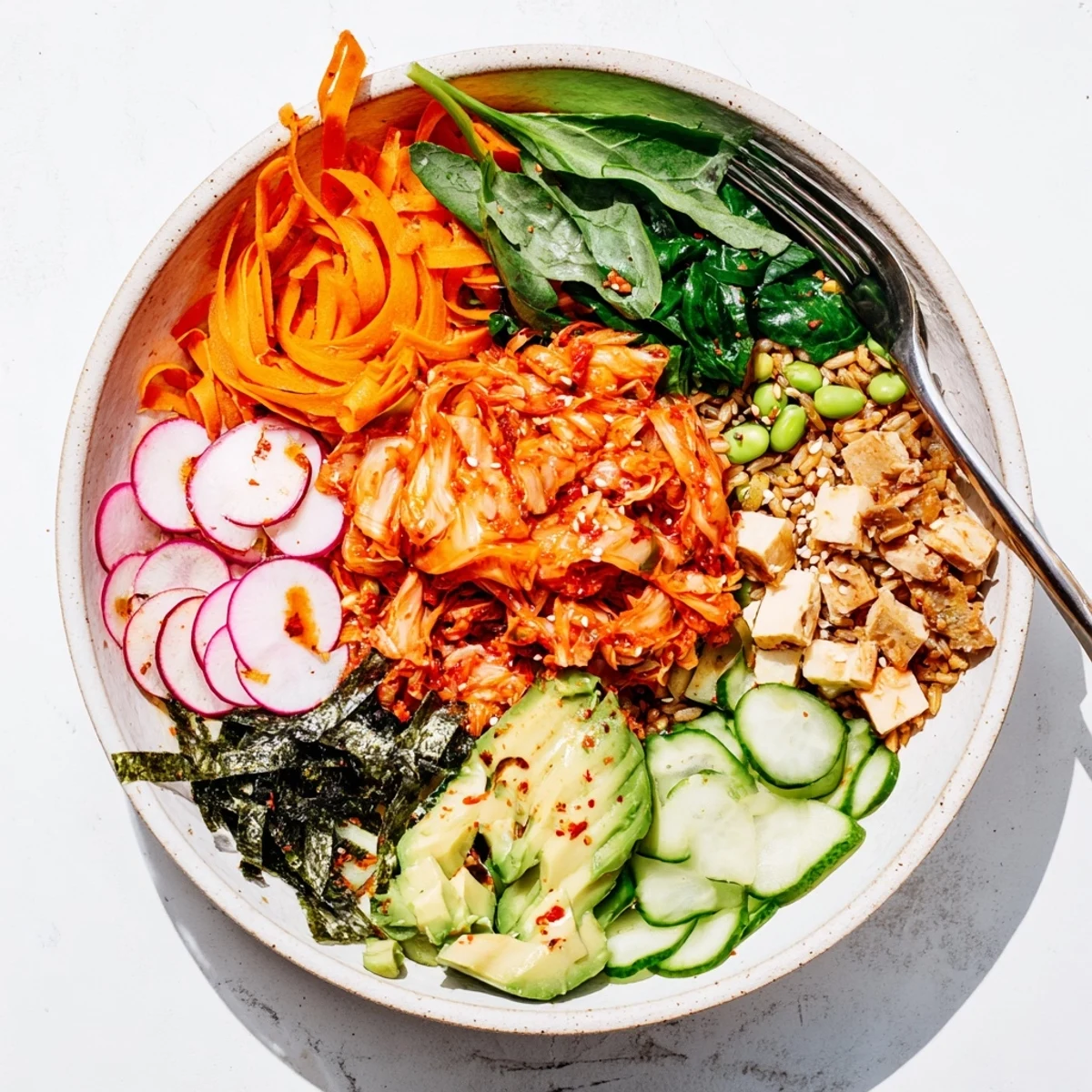 Vibrant fermented vegetable bowl topped with avocado, served with tangy dressing.  