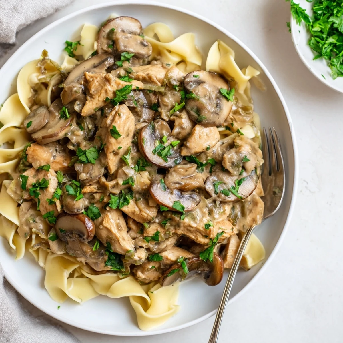 Creamy Chicken Stroganoff served over soft egg noodles with fresh parsley garnish.  