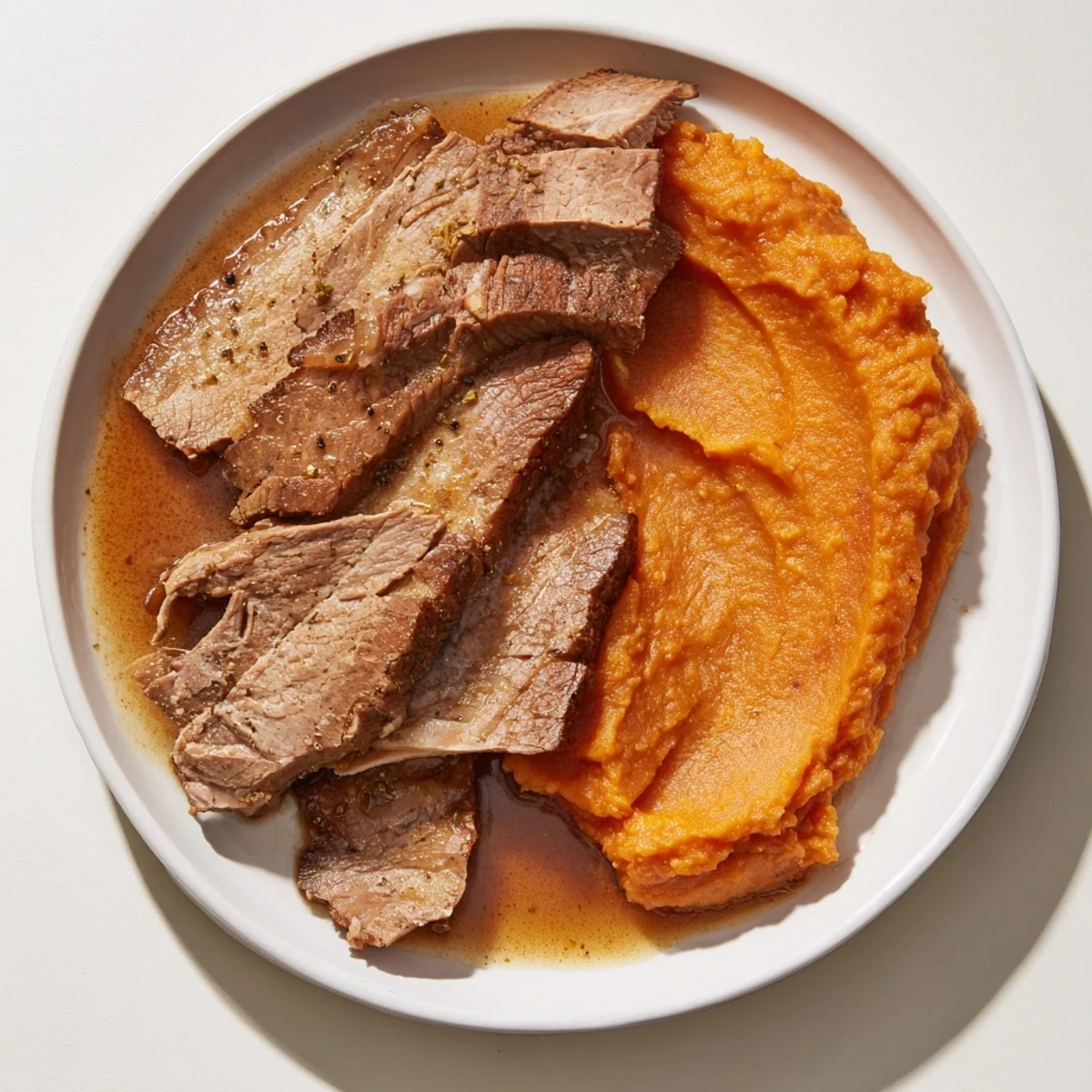 Tender, slow-cooked Classic Brisket with rich gravy, served with fluffy mashed sweet potatoes.