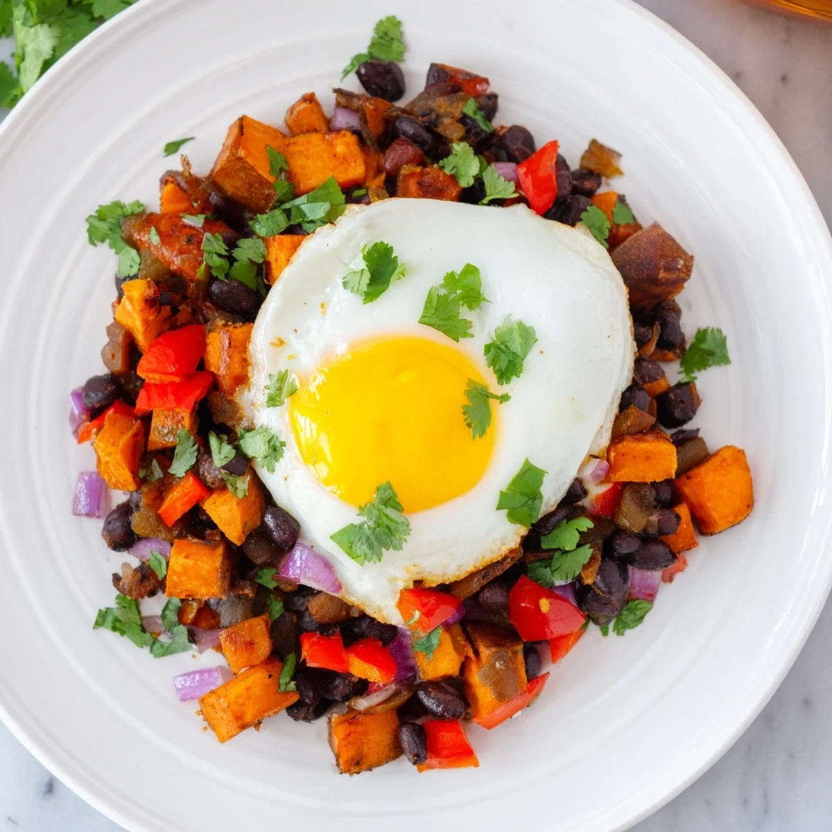 Golden-brown Sweet Potato & Black Bean Breakfast Hash topped with perfectly cooked sunny-side-up eggs.