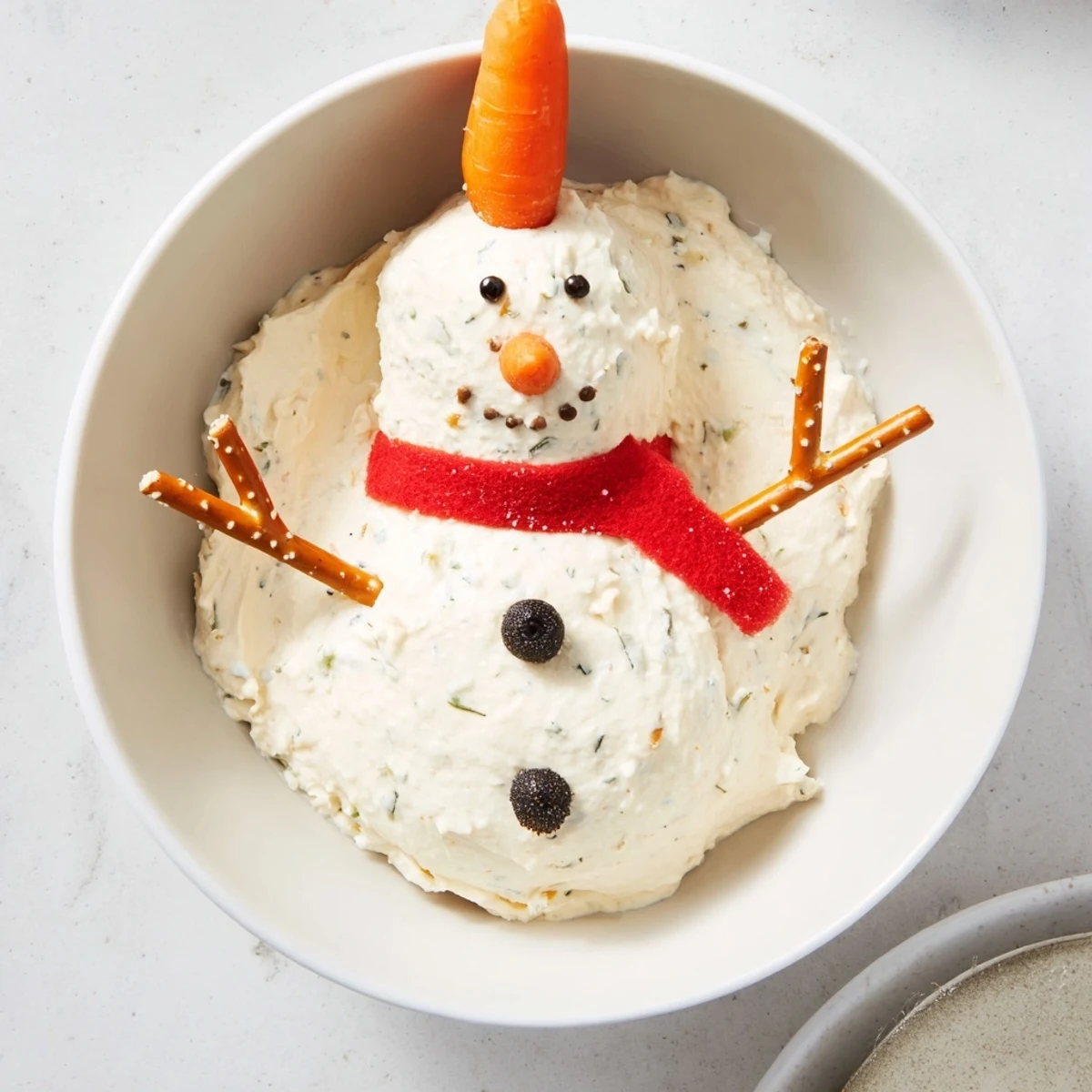 Festive Melted Snowman Dip, a holiday appetizer featuring a melted cheese snowman, served with crackers.