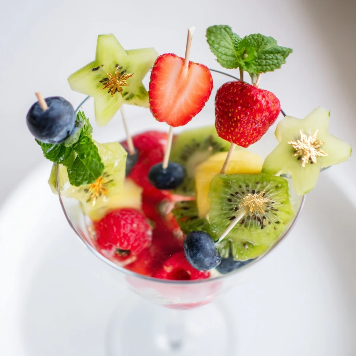 Fresh fruit garnishes adorn champagne flutes, showcasing a festive arrangement for New Year's celebrations.