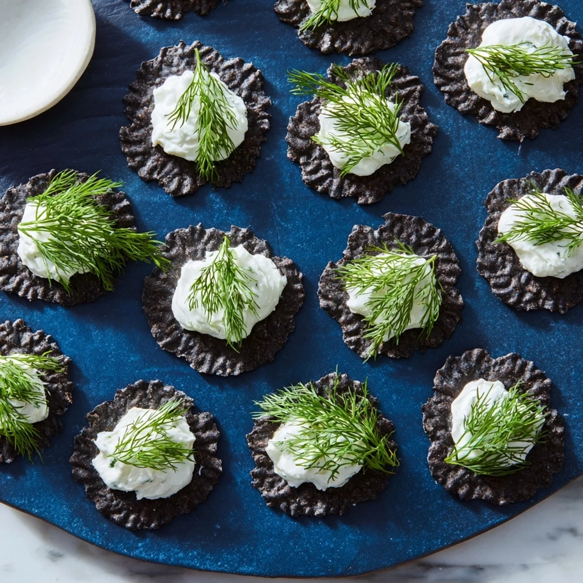 Enjoy a visually stunning The Stormy Sea appetizer of sea-inspired crackers, cheese, and dill, perfect for sharing.