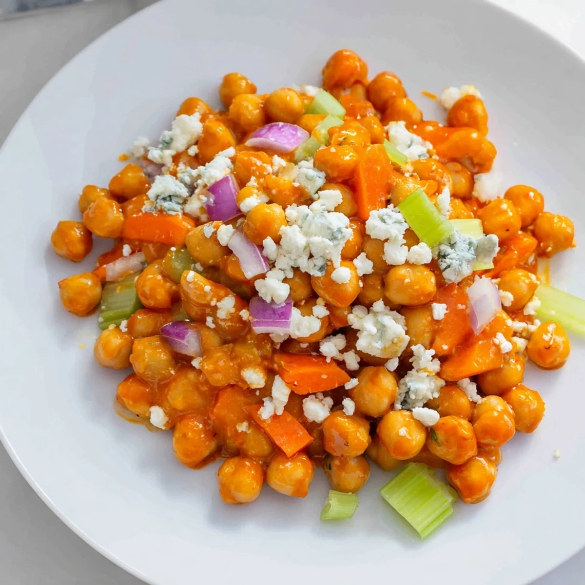 Vibrant buffalo chicken bean salad, with creamy blue cheese crumbles atop a flavorful chickpea base.