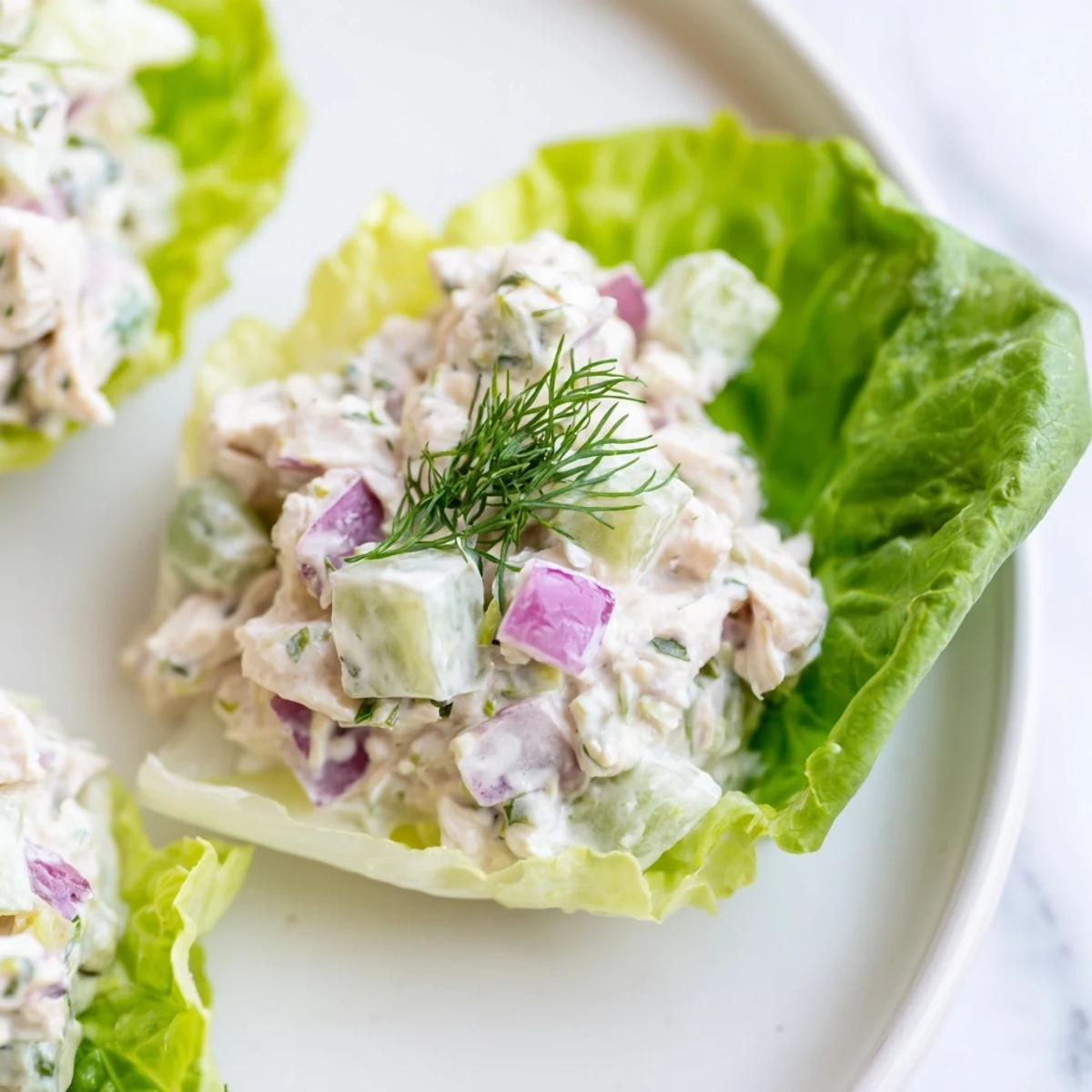Hearty Dill Pickle Chicken Salad Lettuce Cups filled with chunky chicken, crunchy pickles, and herbs on a green platter.
