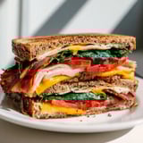 A close-up of a delicious Turkey Bacon, Spinach & Tomato Grilled Cheese, ready to be sliced in half.