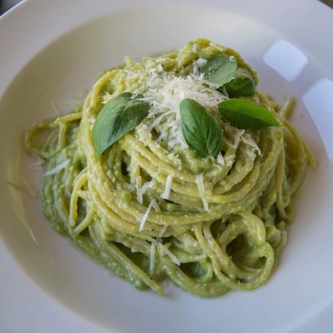 Creamy avocado pasta, a vibrant green dish topped with fresh basil and Parmesan cheese.