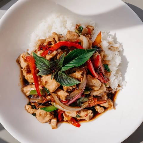 A steaming Thai Basil Chicken Bowl with vibrant bell peppers and fragrant basil.