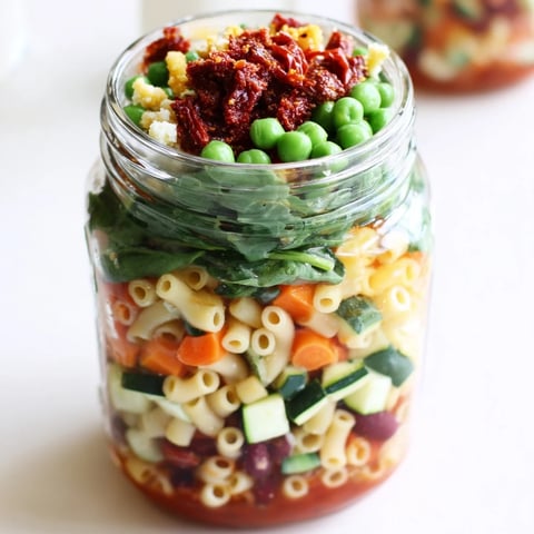Minestrone soup in jar layered beautifully with pasta and vibrant vegetables, ready to eat.