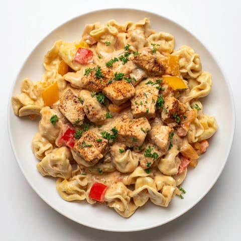 A steaming bowl of Zesty Cajun Garlic Parmesan Chicken Tortellini, showcasing tender chicken and flavorful sauce.