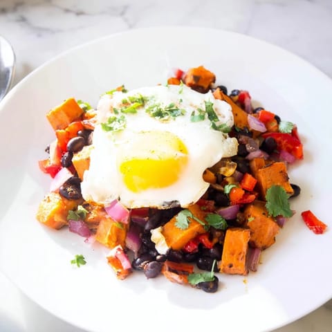 Sizzling skillet of Sweet Potato & Black Bean Breakfast Hash, garnished with fresh cilantro; ready to serve.