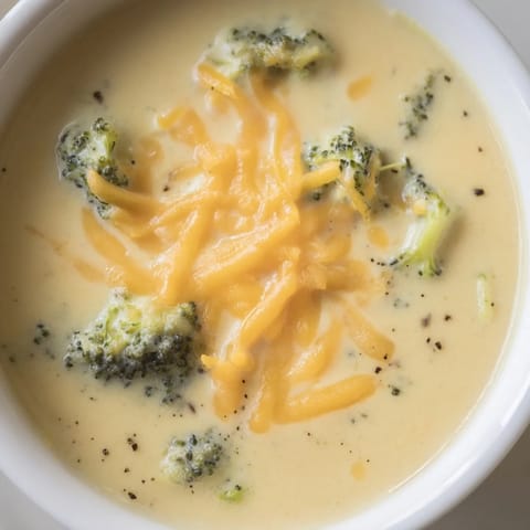 Velvety smooth Broccoli Cheese Soup, garnished with cheese, ready to be served hot.