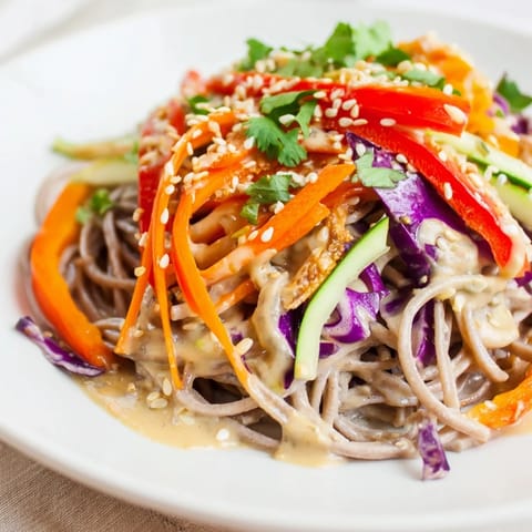 Chilled soba noodle salad tossed with sesame dressing, garnished with cilantro and sesame seeds.