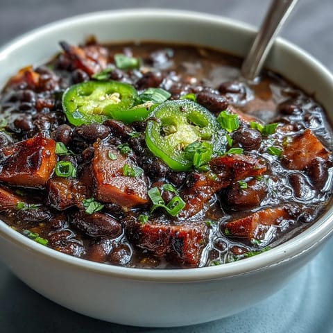 Hearty black bean and ham soup with jalapeños, topped with fresh cilantro and lime wedges for a spicy kick.  