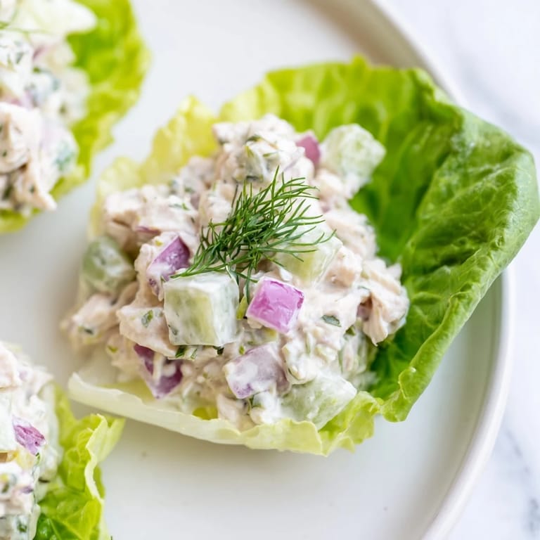 Hearty Dill Pickle Chicken Salad Lettuce Cups filled with chunky chicken, crunchy pickles, and herbs on a green platter.