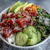 Spicy tuna poke bowl with marinated sushi-grade tuna, avocado, cucumber, and seaweed over seasoned rice.